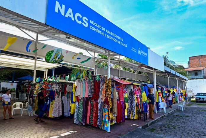 A combinação entre os festejos juninos e a expectativa pela Copa do Mundo tem aquecido o movimento nas feiras e mercados municipais administrados pela Prefeitura de Salvador, por meio da Secretaria Municipal de Ordem Pública (Semop). Com a chegada de junho, os consumidores já começam a procura pelos produtos típicos da época, e, neste ano, buscam também camisas da Seleção e adereços nas cores da bandeira do Brasil. Atualmente, o poder público municipal faz a gestão de 20 feiras e 14 mercados municipais, reunindo cerca de mil vendedores que comercializam diariamente produtos variados. No Núcleo de Abastecimento, Comércio e Serviços (NACS) Itapuã, um dos principais centros de abastecimento da capital baiana, o fluxo de clientes tem crescido em busca de itens tradicionais como milho, amendoim, laranja, licor, bolos e outros produtos que compõem as celebrações juninas. No local, os clientes também encontram itens relacionados à Copa do Mundo. A expectativa dos permissionários é de que este período represente um dos melhores momentos do ano para o comércio. Veterana da feira, Jandiara Santos de Araújo Ribeiro, conhecida como Pretinha, trabalha há 46 anos no comércio de produtos típicos. Aos 61 anos, ela aposta no aumento das vendas impulsionado pelo São João e Copa do Mundo. "Está tudo junto este ano. A expectativa é boa. Estou esperando que as vendas cresçam bastante nos próximos dias", afirma. Há 24 anos trabalhando no local, a comerciante Josilene Trindade, de 58 anos, apelidada de Leninha, já percebe os primeiros reflexos da temporada. Na barraca dela, não faltam milho, amendoim, laranja e licores. "Já teve um aumento na venda de amendoim, mas espero que melhore ainda mais com o início dos jogos. O milho sai a cinco espigas por R$ 10 e o licor custa R$ 35. A expectativa é muito boa", conta. Os quitutes juninos também já movimentam os corredores do NACS Itapuã. Há quase três décadas atuando entre a Feira de Itapuã e o Núcleo de Abastecimento, Renilda Maiara, de 55 anos, comemora a procura antecipada por bolos, pamonhas e canjicas. "O bolo de aipim é o campeão de vendas. Já estamos atendendo festas de empresas, buffets e eventos. Só para uma festa recente foram mais de 300 porções de canjica e pamonha. Graças a Deus, a procura já começou", relata. Nas barracas de vestuário, o clima é de Copa do Mundo. A comerciante Kauane Stephany, de 24 anos, diz que as camisas da Seleção Brasileira lideram as vendas neste período. "Quando os clientes aparecem, acabam levando as camisas do Brasil. Estou mais ansiosa pela Copa do que pelo São João, porque geralmente as vendas aumentam bastante", diz. A coordenadora de Feiras e Mercados da Semop, Fabiana Moura, afirma que a Prefeitura tem atuado para garantir que os equipamentos estejam preparados para atender ao aumento da demanda. "Os mercados municipais são espaços importantes para a economia local e a preservação das nossas tradições culturais. Com a chegada dos festejos juninos e a mobilização em torno da Copa do Mundo, observamos uma procura maior por produtos típicos e a expectativa é de um crescimento ainda mais expressivo nas vendas ao longo do mês", diz. Segundo a coordenadora, a gestão municipal mantém ações permanentes de ordenamento, limpeza e fiscalização nos mercados, garantindo melhores condições de funcionamento para comerciantes e mais conforto para a população que frequenta os espaços. Além do NACS de Itapuã, outros equipamentos administrados pela Prefeitura também estão abastecidos para o período, a exemplo do Mercado Popular de Água de Meninos, Mercado de Cajazeiras e Mercado de São Cristóvão, entre outros. Confira o funcionamento dos mercados no período junino: 20 de junho (sábado) Mercado Popular: 6h às 16h Mercado do Bonfim: bares: 11h às 22h; artesanato: 9h às 17h NACS de Itapuã: 6h às 18h Mercado das Flores: 8h às 17h Mercado Dois de Julho: 7h às 17h Mercado de Itapuã: 6h às 19h NACS de Periperi: 6h às 19h Mercado de Cajazeiras: 7h às 17h Mercado São Miguel: 8h às 17h Mercado Modelo: 9h às 18h Mercado Jardim Cruzeiro: 8h às 17h Mercado Municipal São Cristóvão: 7h às 17h Mercado Fazenda Coutos: 7h às 17h Mercado do Curtume: 7h à 0h Mercado da Liberdade: 7h às 20h Mercado Mané Dendê: 7h às 17h 21 de junho (domingo) Mercado Popular: 6h às 12h Mercado do Bonfim: bares: 11h às 22h; artesanato: 9h às 17h NACS de Itapuã: 6h às 13h Mercado das Flores: fechado Mercado Dois de Julho: 7h às 13h Mercado de Itapuã: 7h às 17h NACS de Periperi: 6h às 12h Mercado de Cajazeiras: fechado Mercado São Miguel: 8h às 15h Mercado Modelo: 9h às 14h Mercado Jardim Cruzeiro: 8h às 12h Mercado Municipal São Cristóvão: 7h às 13h Mercado Fazenda Coutos: 7h às 12h Mercado do Curtume: 7h à 0h Mercado da Liberdade: fechado Mercado Mané Dendê: 7h às 13h 22 de junho (segunda-feira) Mercado Popular: 6h às 12h Mercado do Bonfim: bares: 11h às 22h; artesanato: 9h às 17h NACS de Itapuã: 6h às 14h Mercado das Flores: 8h às 17h Mercado Dois de Julho: 7h às 13h Mercado de Itapuã: 7h às 17h NACS de Periperi: 6h às 19h Mercado de Cajazeiras: 7h às 17h Mercado São Miguel: 8h às 15h Mercado Modelo: 9h às 14h Mercado Jardim Cruzeiro: 8h às 17h Mercado Municipal São Cristóvão: 7h às 13h Mercado Fazenda Coutos: 7h às 12h Mercado do Curtume: 7h às 15h Mercado da Liberdade: 7h às 17h Mercado Mané Dendê: 7h às 17h 23 de junho (terça-feira) Mercado Popular: 5h às 16h Mercado do Bonfim: bares: 11h às 22h; artesanato: 9h às 16h NACS de Itapuã: 6h às 18h Mercado das Flores: 8h às 15h Mercado Dois de Julho: 7h às 18h Mercado de Itapuã: 8h às 19h NACS de Periperi: 6h às 19h Mercado de Cajazeiras: 7h às 17h Mercado São Miguel: 8h às 17h Mercado Modelo: 9h às 15h Mercado Jardim Cruzeiro: 8h às 17h Mercado Municipal São Cristóvão: 7h às 18h Mercado Fazenda Coutos: 7h às 17h Mercado do Curtume: fechado Mercado da Liberdade: fechado Mercado Mané Dendê: 7h às 17h 24 de junho (quarta-feira – São João) Mercado Popular: fechado Mercado do Bonfim: bares: 11h às 22h NACS de Itapuã: 6h às 18h Mercado das Flores: fechado Mercado Dois de Julho: 7h às 15h Mercado de Itapuã: 8h às 15h NACS de Periperi: 7h às 12h Mercado de Cajazeiras: fechado Mercado São Miguel: restaurantes: 8h às 15h Mercado Modelo: fechado Mercado Jardim Cruzeiro: 8h às 12h Mercado Municipal São Cristóvão: fechado Mercado Fazenda Coutos: fechado Mercado do Curtume: fechado Mercado da Liberdade: fechado Mercado Mané Dendê: fechado